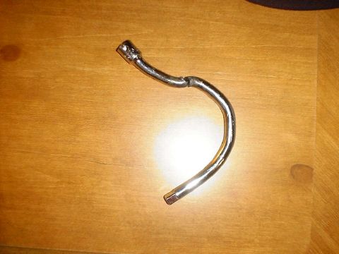1988 Ford Bronco - A bent metal pipe with socket ends is shown on a wooden surface. The registry claims it is from a 1988 Ford Bronco, but this is unlikely.