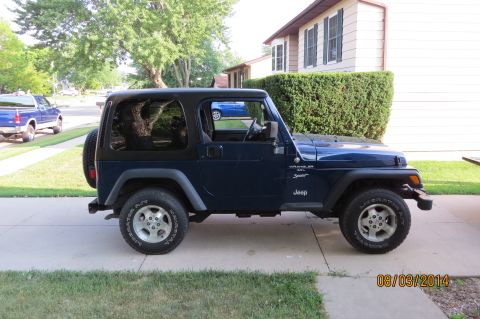 2000 Jeep Wrangler - A blue Jeep Wrangler is parked on a driveway in front of a house.