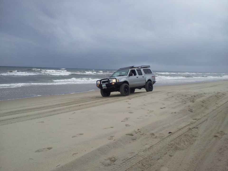 Silver pickup truck with camper shell on beach, 2003 Nissan Frontier