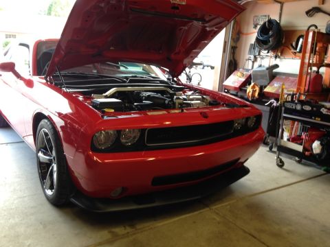 2010 Dodge Challenger - A red 2010 Dodge Challenger is parked in a garage with its hood open, revealing the engine compartment.
