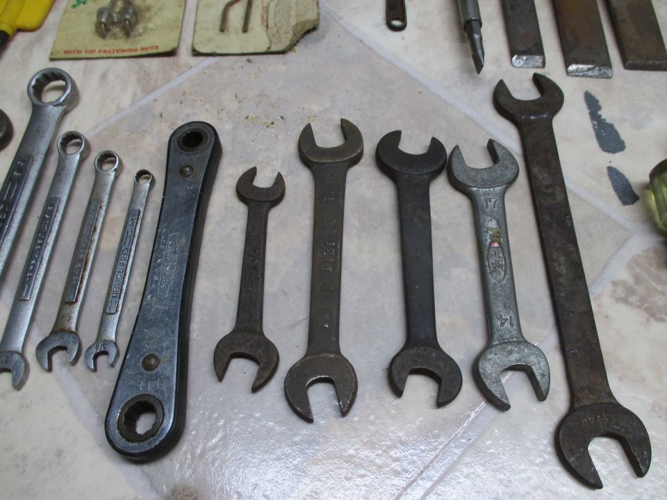 Assortment of metal wrenches and tools laid out on a tiled surface