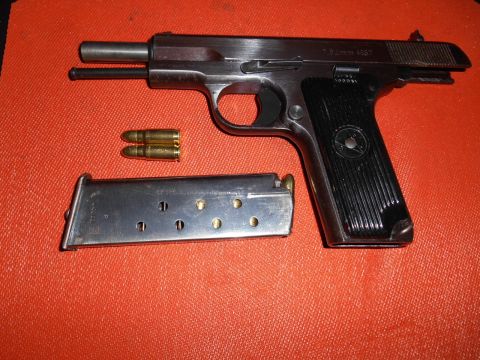 1994 Ford Bronco - A pistol, magazine, and ammunition are laid out on an orange surface. The pistol is marked "7.62mm M57".
