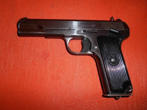 1994 Ford Bronco - A side view of a 7.62mm M57 pistol against an orange textured background.