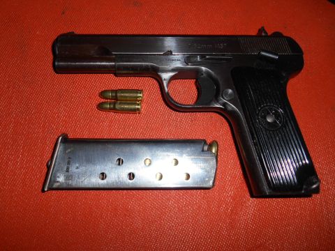 1994 Ford Bronco - Black 7.62mm Tokarev-type pistol marked 7.62mm M57 with detached magazine and two cartridges on a red mat.
