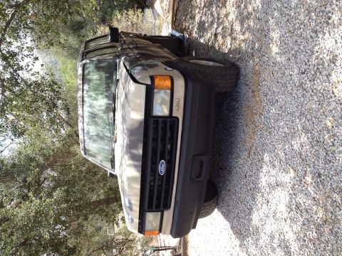 1990 Ford Bronco - This Ford F-Series truck is parked on a gravel surface with trees in the background.