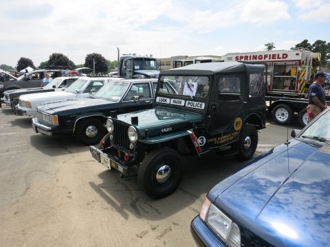 1991 Ford LTD Crown Victoria - green vintage Jeep lettered Look Park Police sits among cruisers and a red Springfield fire truck at an outdoor show.