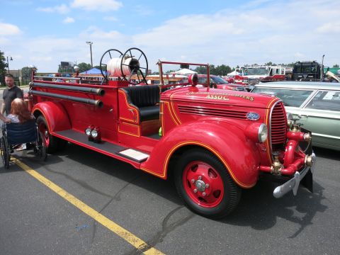 1991 Ford LTD Crown Victoria - restored red antique Ford open-cab fire engine with hose reels and a chrome grille sits gleaming at an outdoor show.