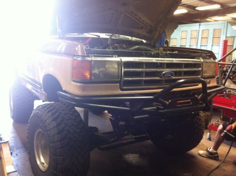 1988 Ford Bronco - This heavily modified Ford truck features a lifted suspension and a custom front bumper. The grille suggests a 1987 model year.