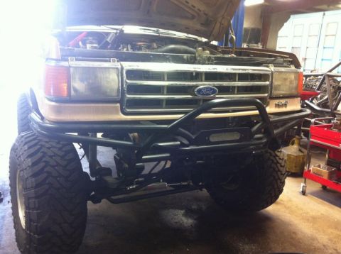 1988 Ford Bronco - This modified Ford Bronco is in a workshop with its hood up, showing off its custom front bumper and winch.