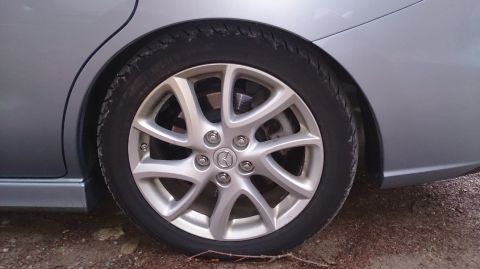 2012 Mazda Mazda 5 - Close-up of the rear wheel and side panel of a silver 2012 Mazda Mazda 5.