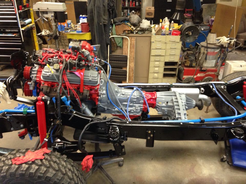 Vehicle chassis with engine and transmission installed, in a workshop setting