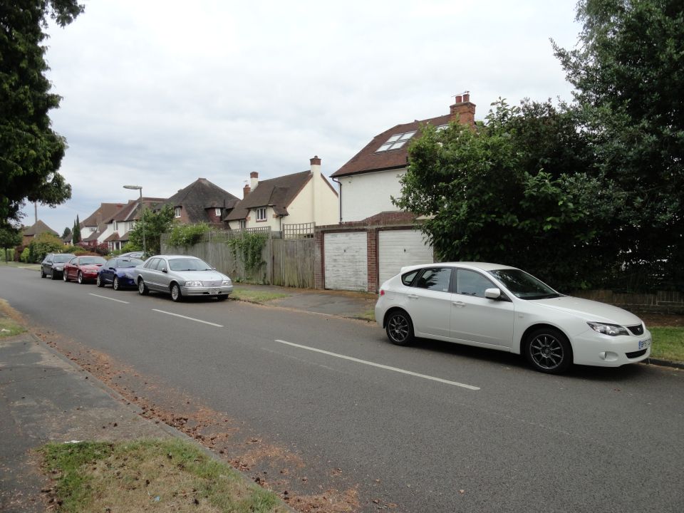 White Subaru Impreza hatchback parked on the right side of a street, with other cars in the background