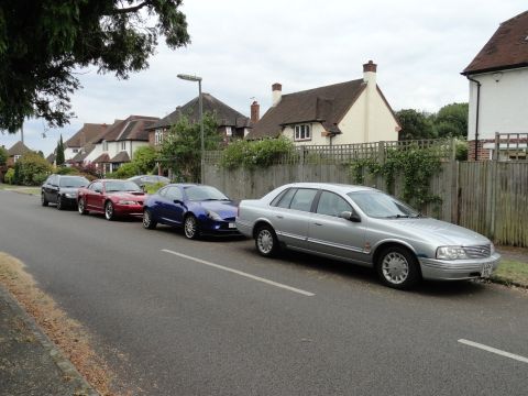 1999 Ford Fairlane - A silver sedan is parked on the side of a street lined with houses, with other vehicles visible in the background.