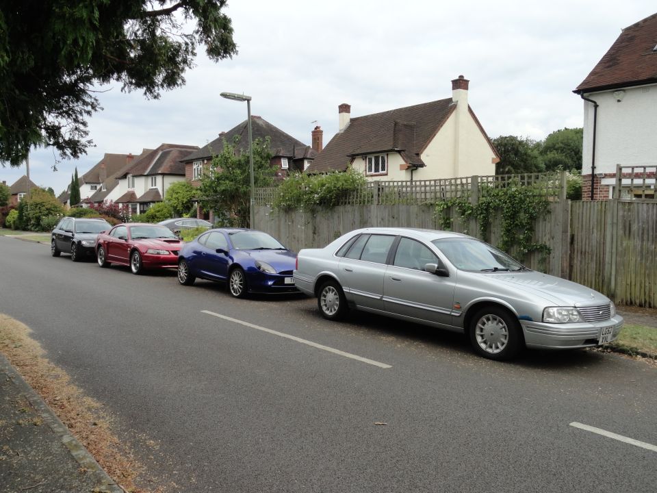 Silver sedan, side view, parked on street. Other cars visible