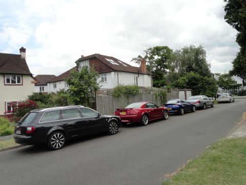 1999 Ford Fairlane - Multiple vehicles are parked along a residential street with houses in the background.