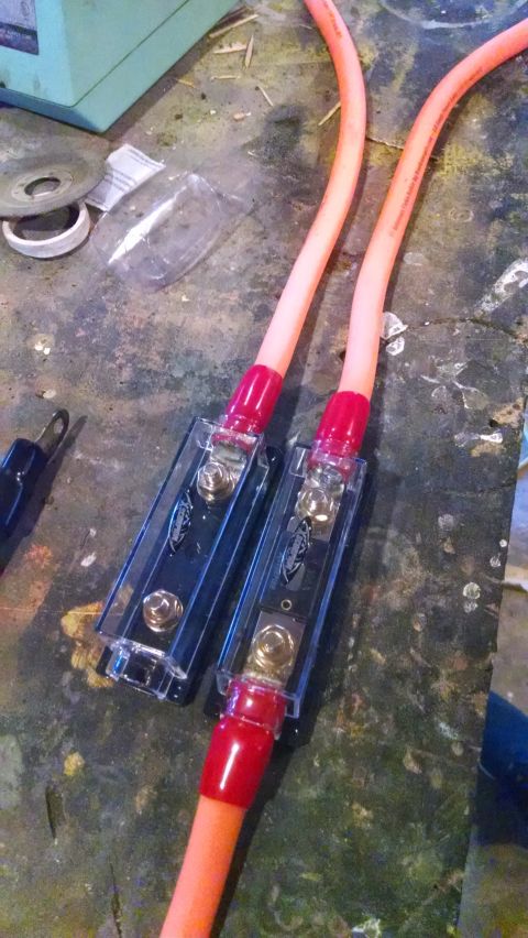 1995 Ford Bronco - Close-up of automotive wiring components, including fuse holders and cables, on a cluttered surface.