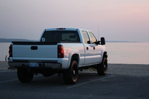 2006 Chevrolet Silverado 2500 - A white 2006 Chevrolet Silverado 2500 is parked near the water at sunset.