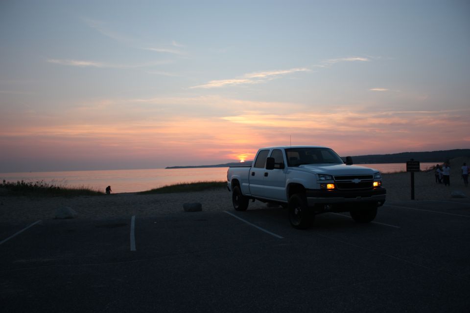 White Chevrolet Silverado pickup truck parked near a beach at sunset