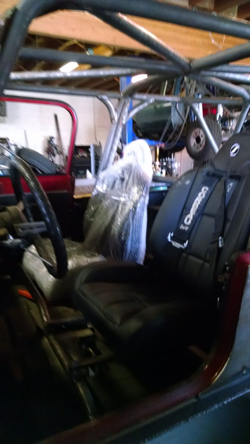 Interior of a Jeep with racing seats and roll cage. "Crower" visible on seat harness