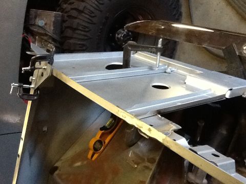 1988 Suzuki Samurai - Metal body panel being worked on with clamps and a level, tire in background.