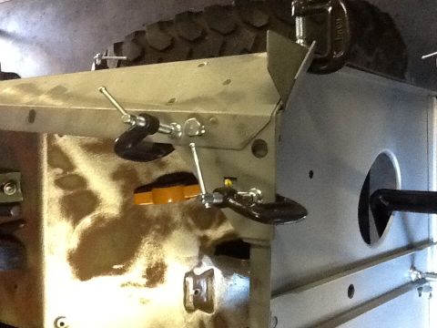 1988 Suzuki Samurai - Vehicle chassis components secured with clamps during work, tire visible overhead.