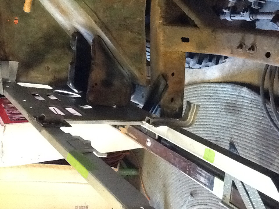 Underside of a vehicle frame with some metal plates and suspension components visible