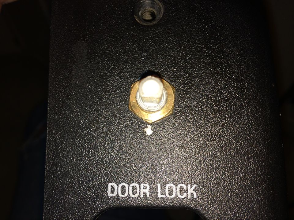 Close-up of a black panel with 'DOOR LOCK' text and a brass-encased switch