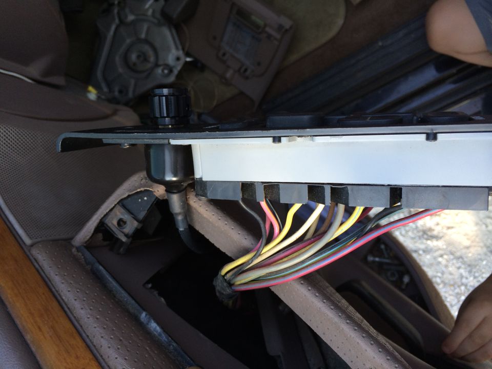 Close-up of a vehicle's interior showing a wiring harness with colorful wires connected to a control module