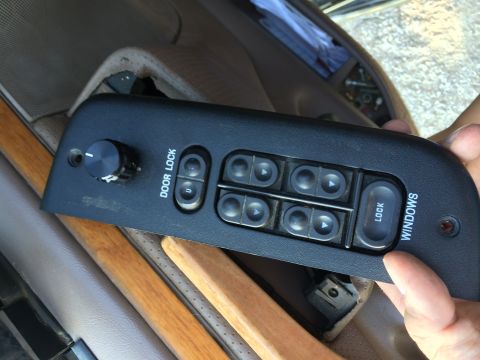 1997 Ford F-350 - A hand holds a removed power window and door lock switch panel from a 1997 Ford F-350.