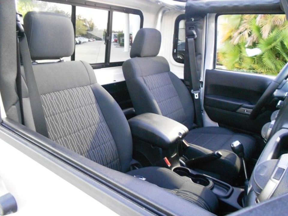 Interior of a white Jeep Wrangler showing front seats, center console, and dashboard