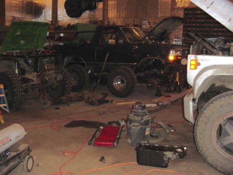 1992 Ford Bronco - Multiple vehicles are undergoing maintenance in a cluttered garage environment.
