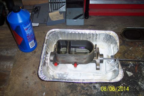 1978 Ford Bronco - A brake master cylinder sits in a foil pan, ready for service, with a bottle of brake fluid to the left.