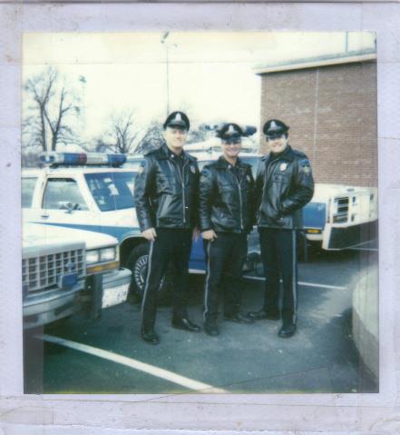 1991 Ford LTD Crown Victoria - Three uniformed officers pose with a 1991 Ford Crown Victoria LTD police car.