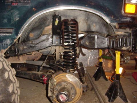 1992 Ford Bronco - The front suspension of a 1992 Ford Bronco is visible, undergoing maintenance with the wheel removed.