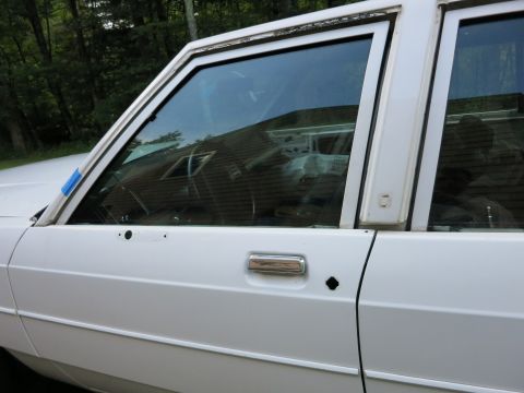 1991 Ford LTD Crown Victoria - Side view of a white sedan, showing the door, window, and chrome door handle.