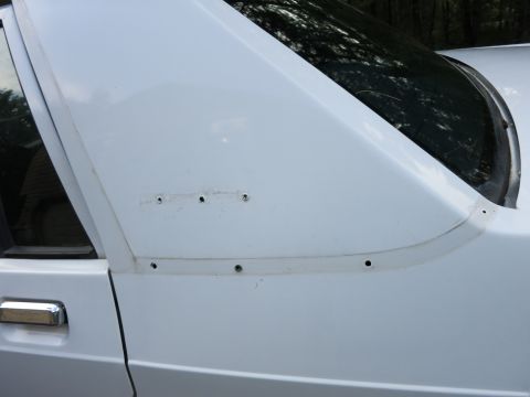 1991 Ford LTD Crown Victoria - Detail of a white car's side panel, including door handle and C-pillar with visible screw holes.