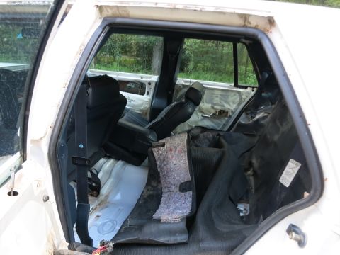 1991 Ford LTD Crown Victoria - The interior of a white vehicle shows signs of disrepair, with torn upholstery and exposed metal components visible.