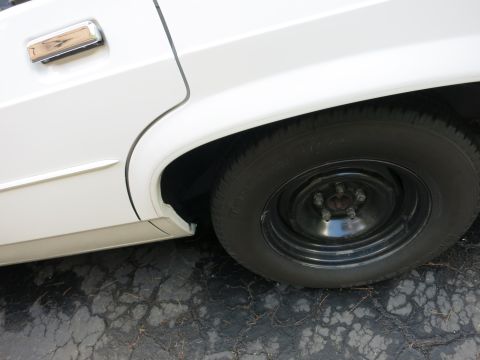 1991 Ford LTD Crown Victoria - Close-up of the rear wheel and door handle of a white 1991 Ford Crown Victoria LTD.