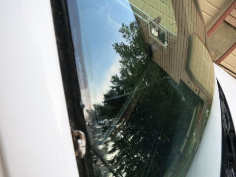 1991 Ford LTD Crown Victoria - Reflection on a car's windshield shows a house and trees under a blue sky.