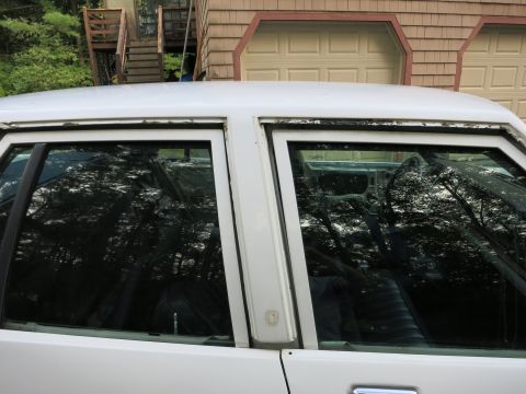 1991 Ford LTD Crown Victoria - Close-up of a white car's side, focusing on window trim and reflections.