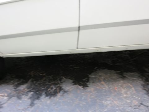 1991 Ford LTD Crown Victoria - The lower section of a white vehicle's body is shown, with a dark, wet surface beneath it is parked on.