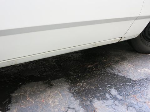 1991 Ford LTD Crown Victoria - Close-up of a white car's lower side panel, showing rivets and minor damage.