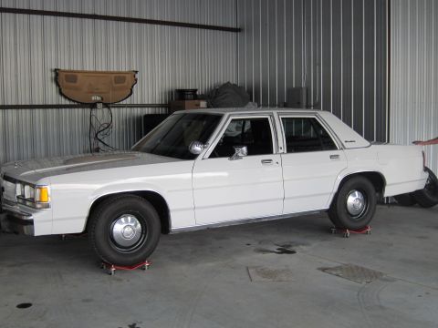 1991 Ford LTD Crown Victoria - White 1991 Ford Crown Victoria LTD is positioned on dollies inside a garage.