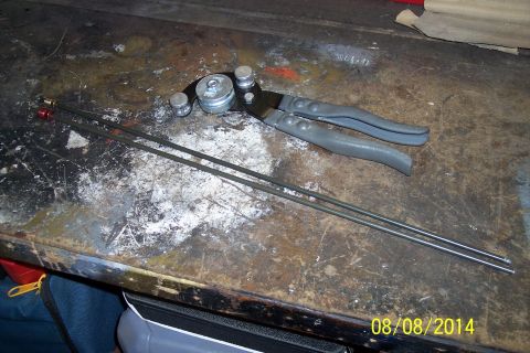 1978 Ford Bronco - A tubing bender and metal rods are on a cluttered workbench.