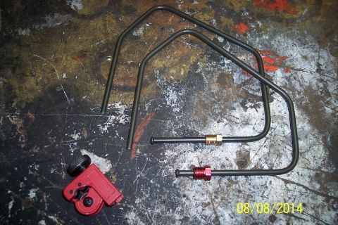 1978 Ford Bronco - A red tubing cutter and several bent metal brake lines with brass and red fittings are laid out on a textured workbench surface.