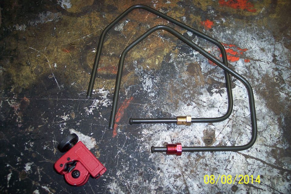 Red tubing cutter and bent metal brake lines with brass and red fittings on a workbench