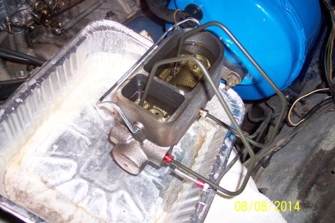 1978 Ford Bronco - Master cylinder assembly with brake fluid in a drip pan, part of a vehicle's braking system.