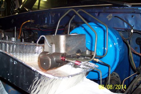 1978 Ford Bronco - Close-up of a vehicle's brake system components, including the master cylinder and booster, with brake fluid collected in a pan.
