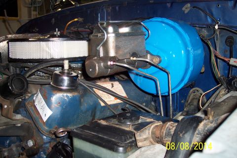 1978 Ford Bronco - Close-up of the engine bay, focusing on the brake booster and master cylinder assembly. A Ford label is visible on the engine component.