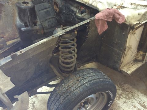1964 Ford Fairlane - Disassembled engine bay and front wheel of a car, showing the suspension and inner fender well.